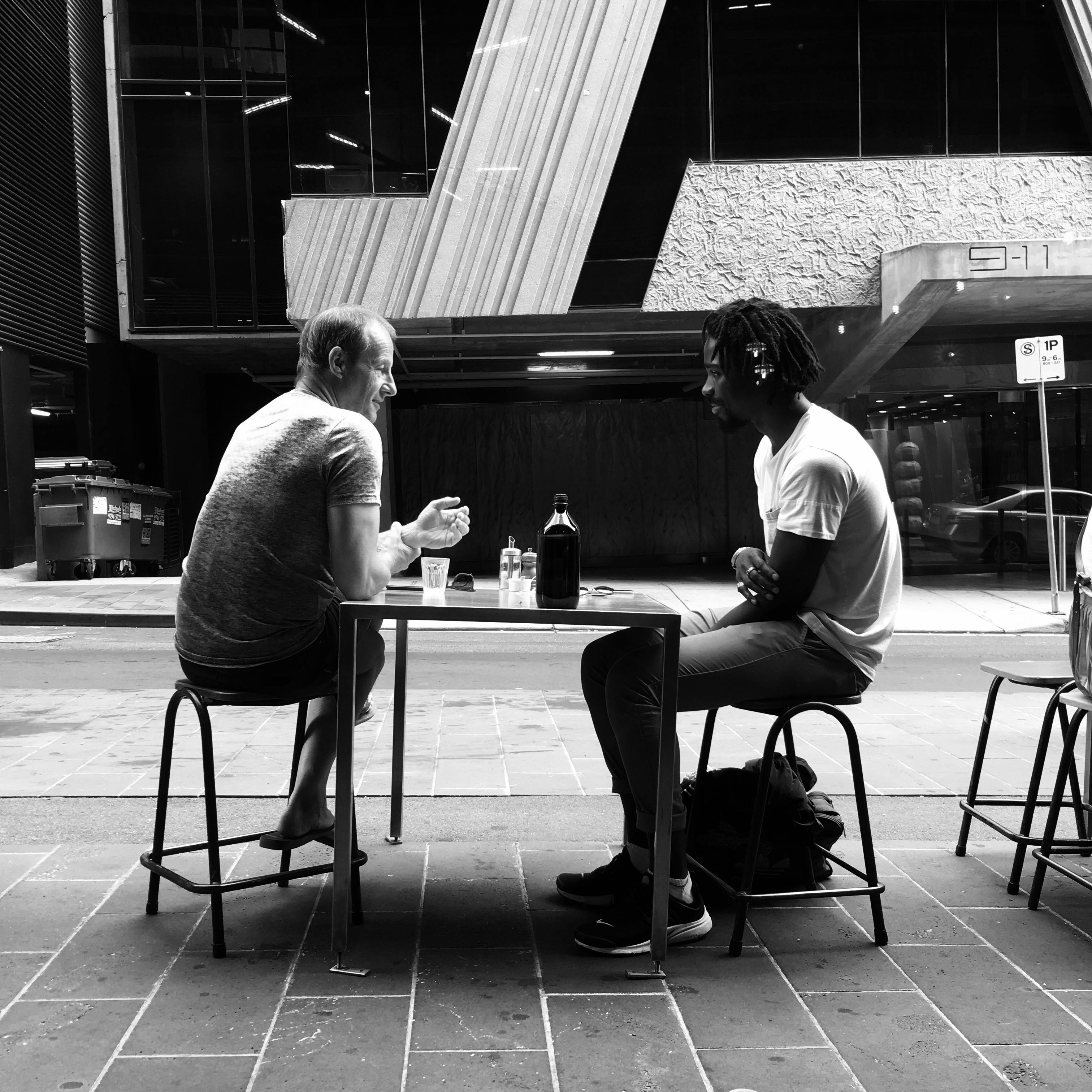 Two friends sitting across from each other at a quiet table.